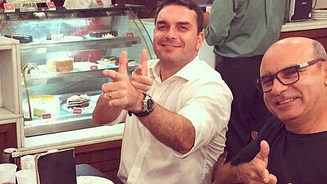 Caros Bolsonaro (esq.) ao lado do miliciano Fabrício Queiroz (dir.)