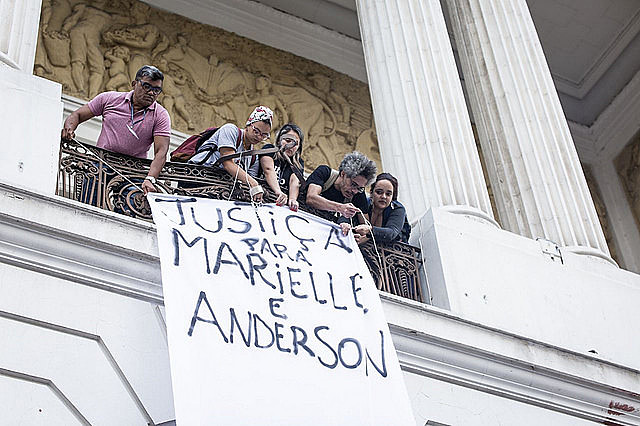Protesters hang banner in honor of the victims and call for justice at Rio's City Council