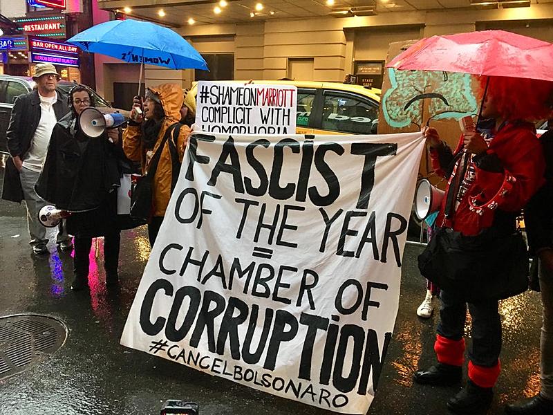 Protester holds banner against Bolsonaro At Americas Society on May 13 in New York City