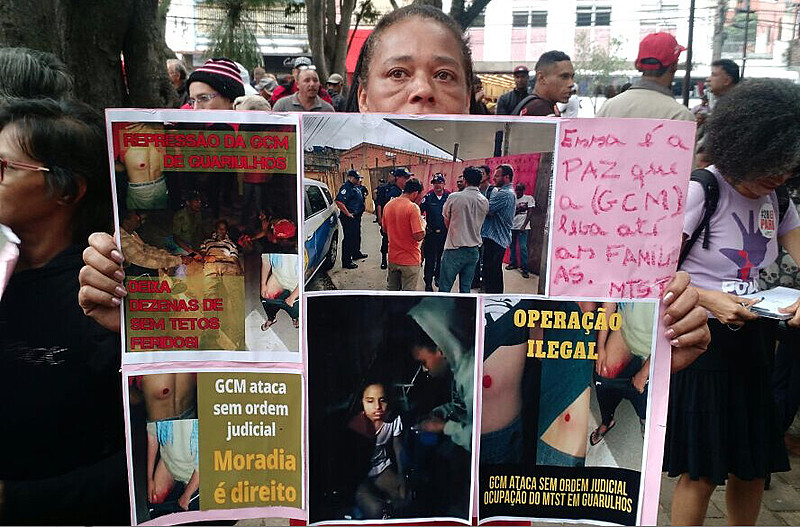 Militante mostra cartaz com fotos de feridos na desocupação de sábado (10)