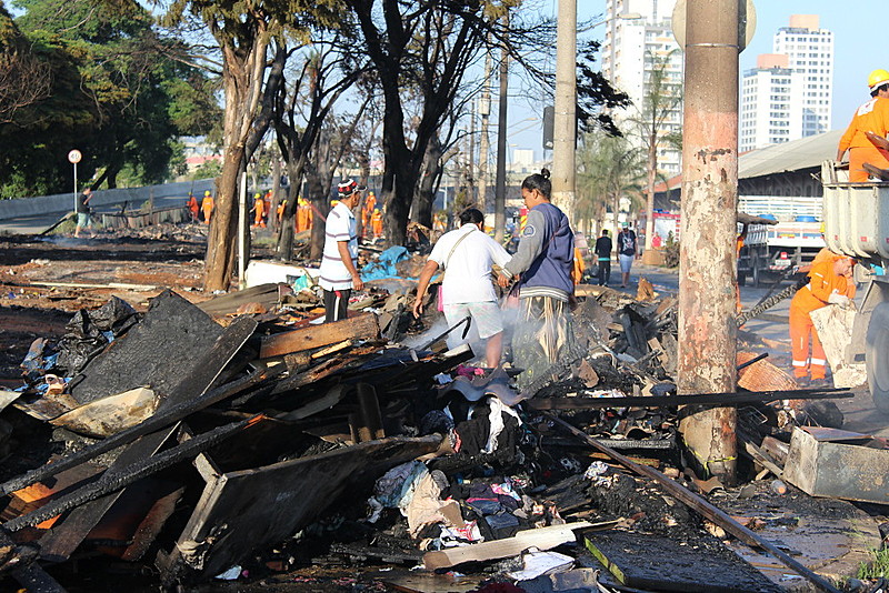 Moradoras buscam pertences nos escombros do incêndio, ocorrido na noite do último sábado (23)