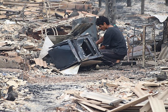 Moradores entre escombros após incêndio em comunidade em dezembro de 2018