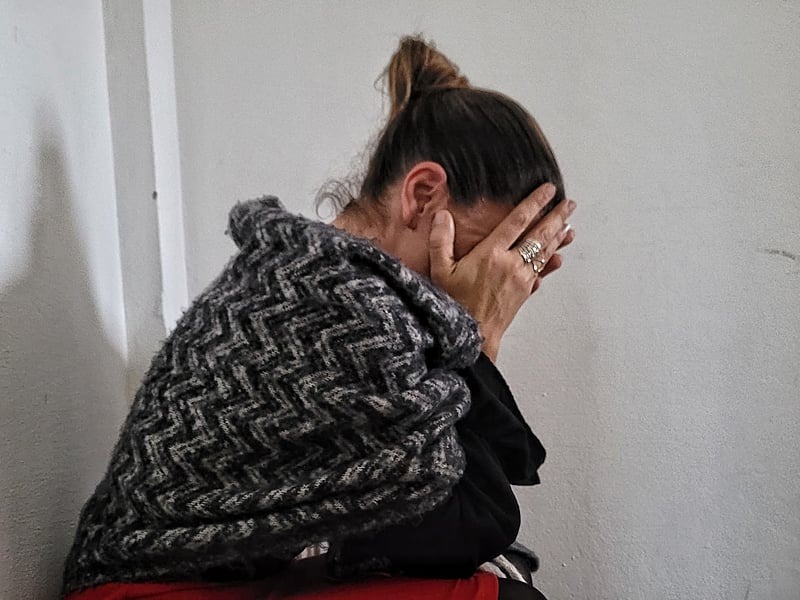 Pessoa sentada aparentando sofrimento com as mãos no rosto