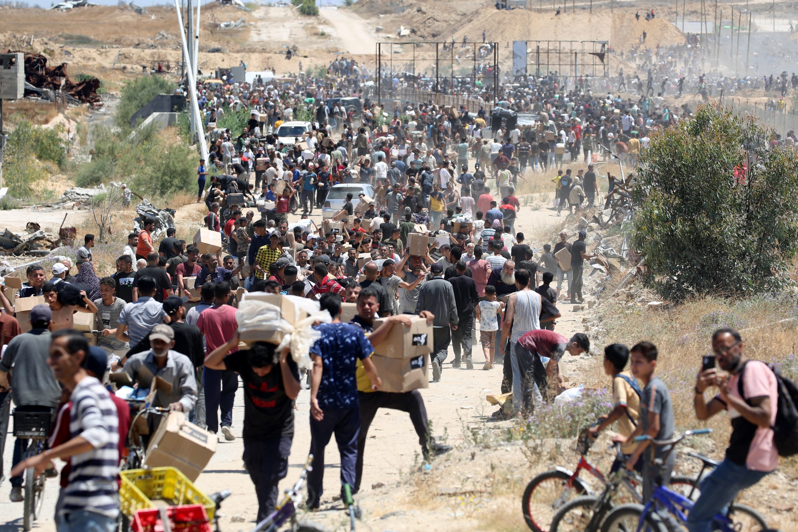 Pessoas carregam caixas de suprimentos de ajuda humanitária da Gaza Humanitarian Foundation (GHF) em 29 de maio de 2025