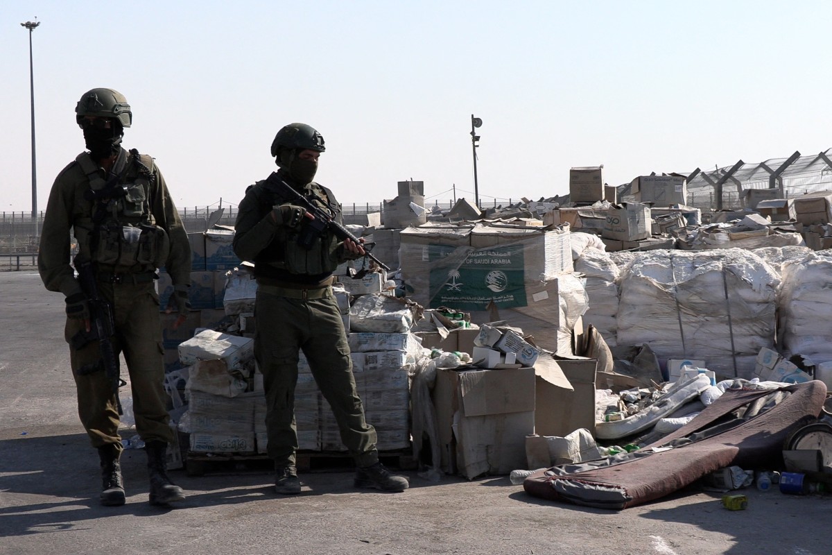 Soldados israelenses montam guarda ao lado de ajuda humanitária na passagem de Kerem Shalom, entre o sul de Israel e a Faixa de Gaza, em 2025