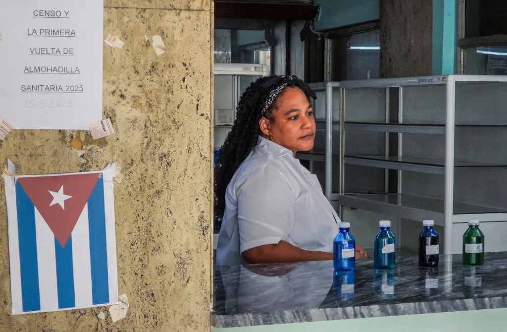 Um farmacêutico está ao lado de frascos de medicamentos fitoterápicos em Havana, em 2 de julho de 2025. (Foto de ADALBERTO ROQUE / AFP)