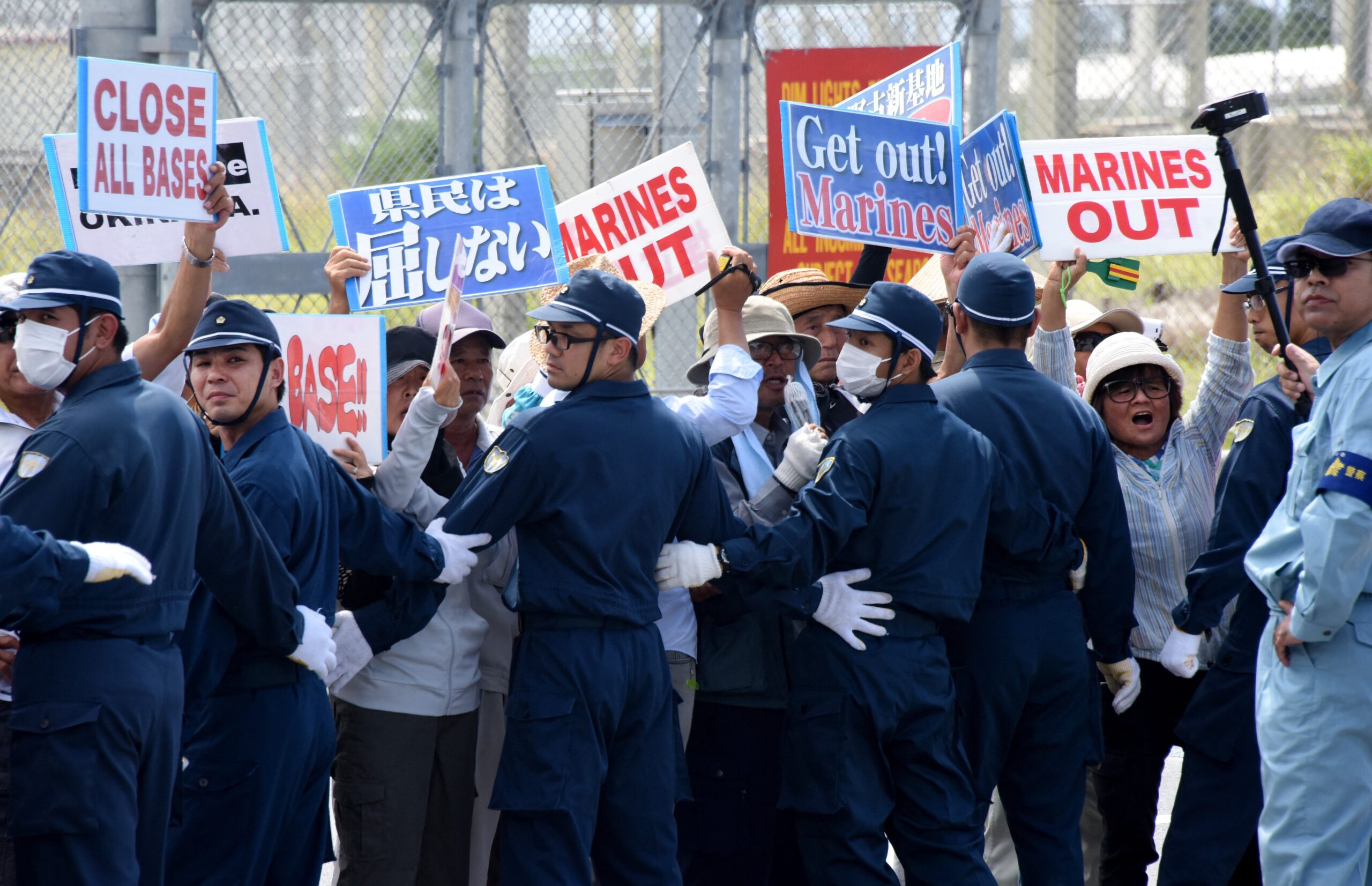 Pessoas protestam contra a presença de bases militares estadunidenses, em frente à base militar Campo Schwab do Corpo de Fuzileiros Navais dos EUA em Nago, na ilha de Okinawa em 17 de junho de 2016.