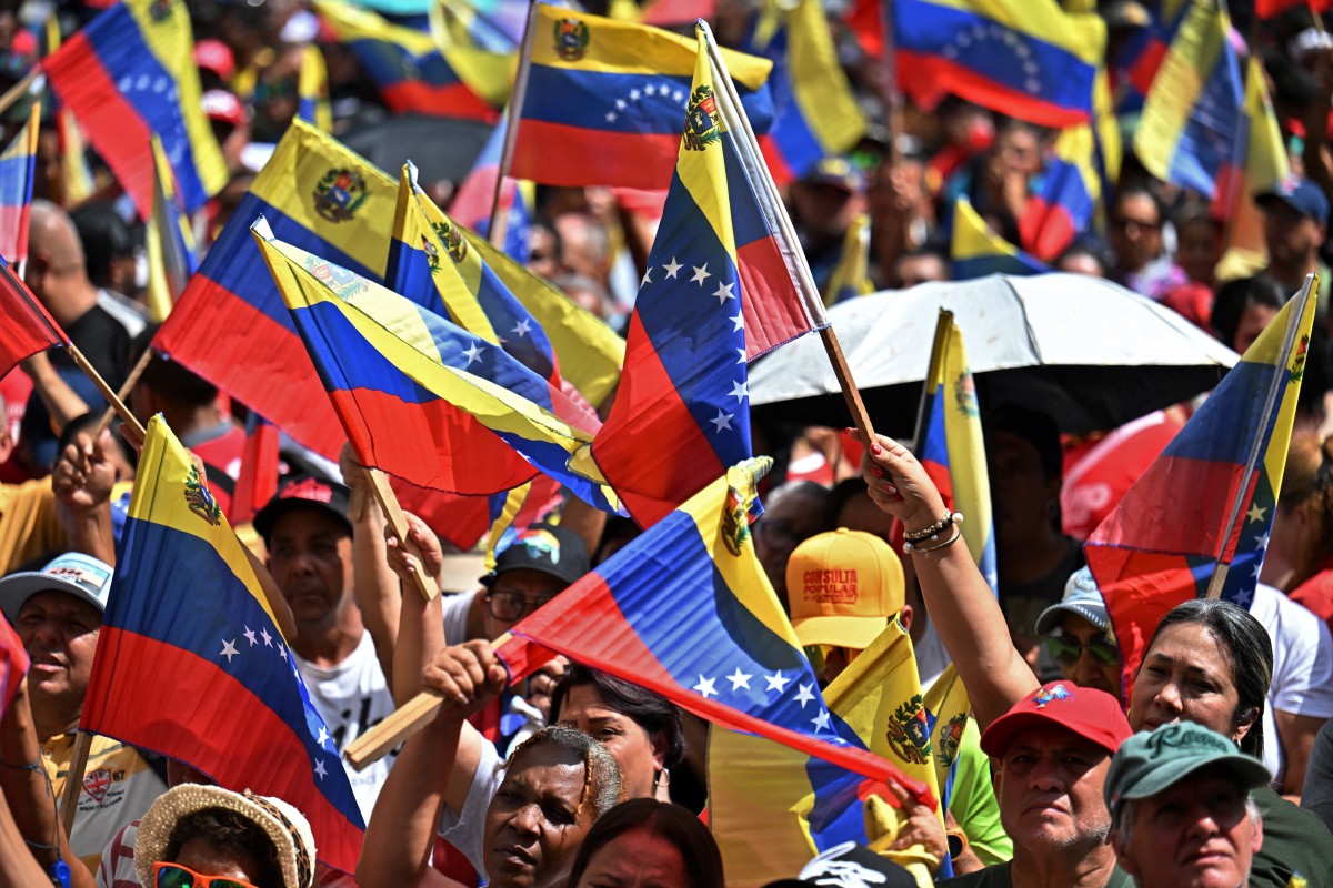 Apoiadores presidente venezuelano sequestrado pelos EUA, Nicolás Maduro, agitam bandeiras nacionais durante uma manifestação em Caracas, em 4 de janeiro de 2026