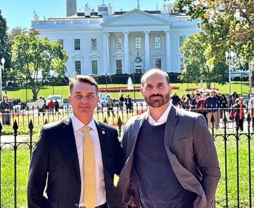O senador Flávio Bolsonaro e o ex-deputado Eduardo Bolsonaro, ambos do PL, posam em frente à Casa Branca.