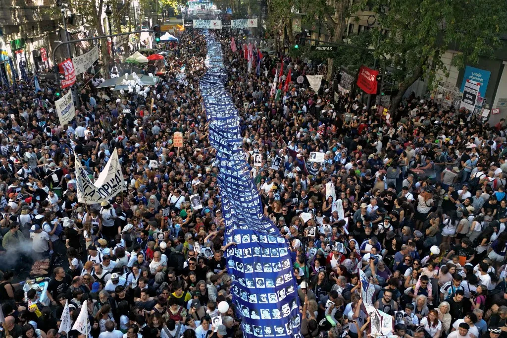 Vista aérea de manifestantes segurando uma faixa com os retratos de pessoas desaparecidas durante uma marcha até a Praça de Maio no 50º aniversário do início da última ditadura militar (1976–1983) em Buenos Aires, em 24 de março de 2026.