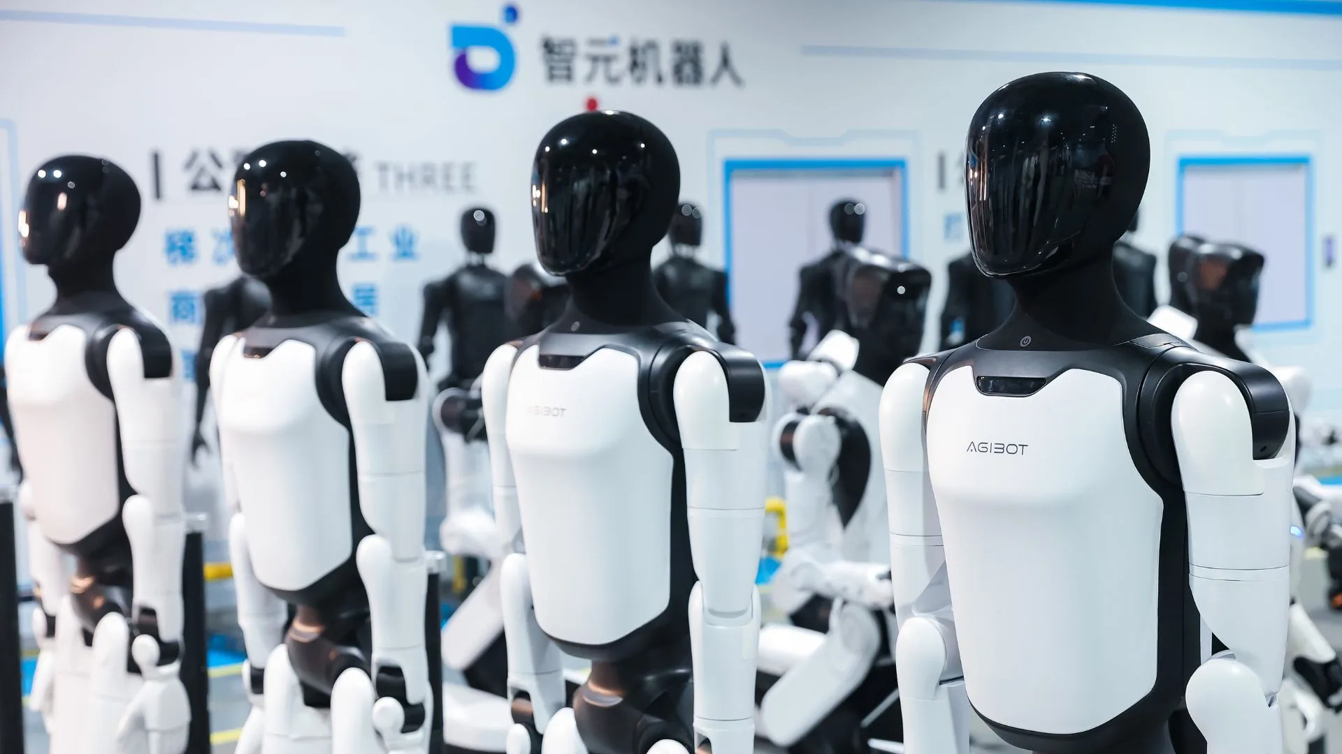 Unidades de robôs humanoides da AgiBot alinhadas em fábrica chinesa, parte de uma rede que inclui produção em grande escala em Foshan, treinamento em cenários reais no centro de Shijingshan, em Pequim, e aplicações industriais em linhas de produção de baterias em Xangai