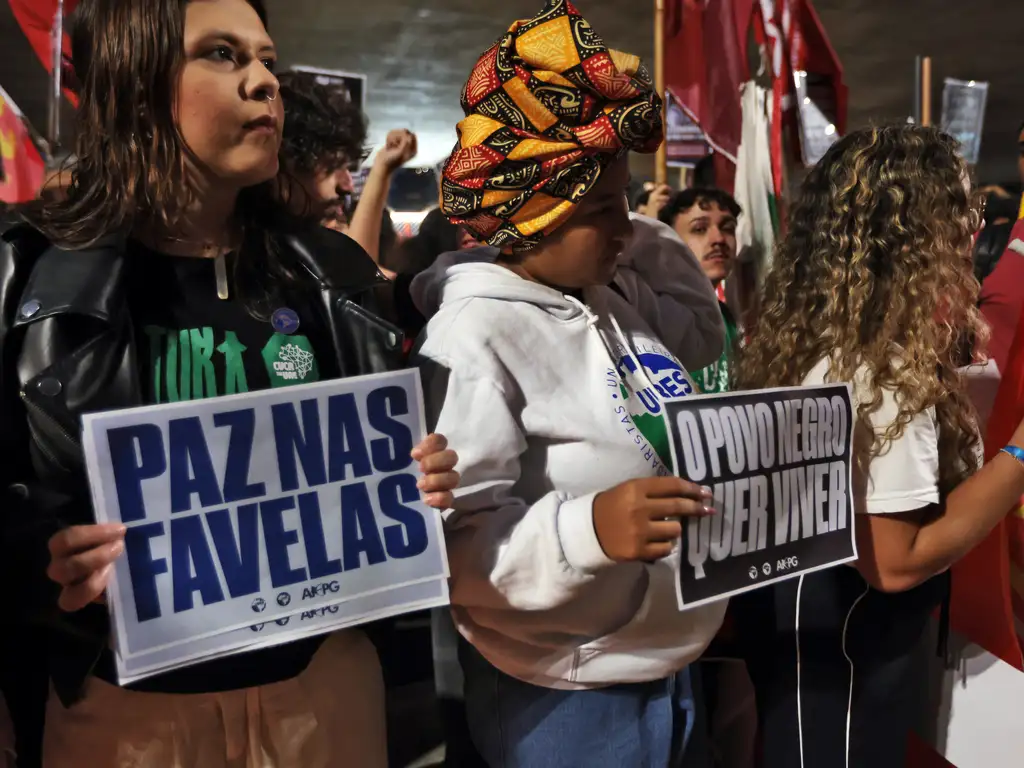Duas mulheres seguram cartazes em que se lê "Paz nas favelas" e "O povo preto quer viver"