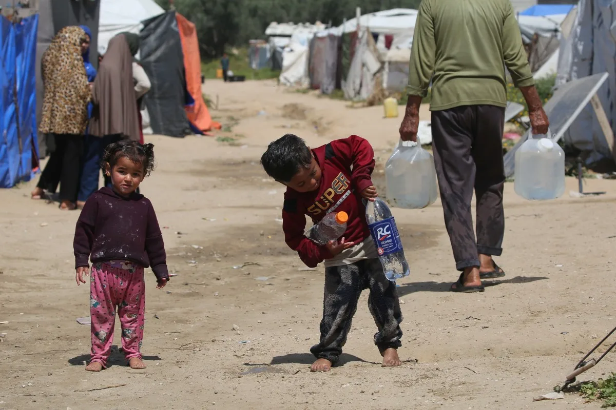 Crianças buscam água potável no campo de refugiados palestinos de Bureij, na região central da Faixa de Gaza, em 28 de abril de 2026