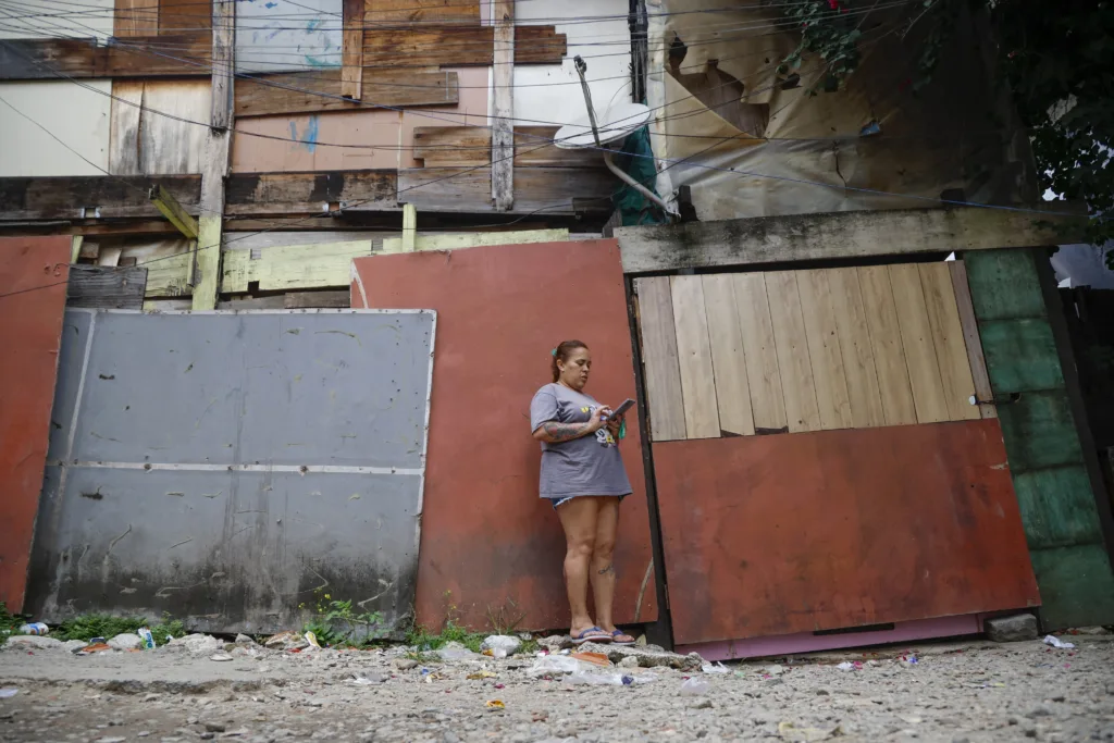 A woman looks at her mobile phone at the Moinho favela during the state government's plan to evict the residents of the community in Sao Paulo, Brazil on April 22, 2025. (Photo by Miguel SCHINCARIOL / AFP)