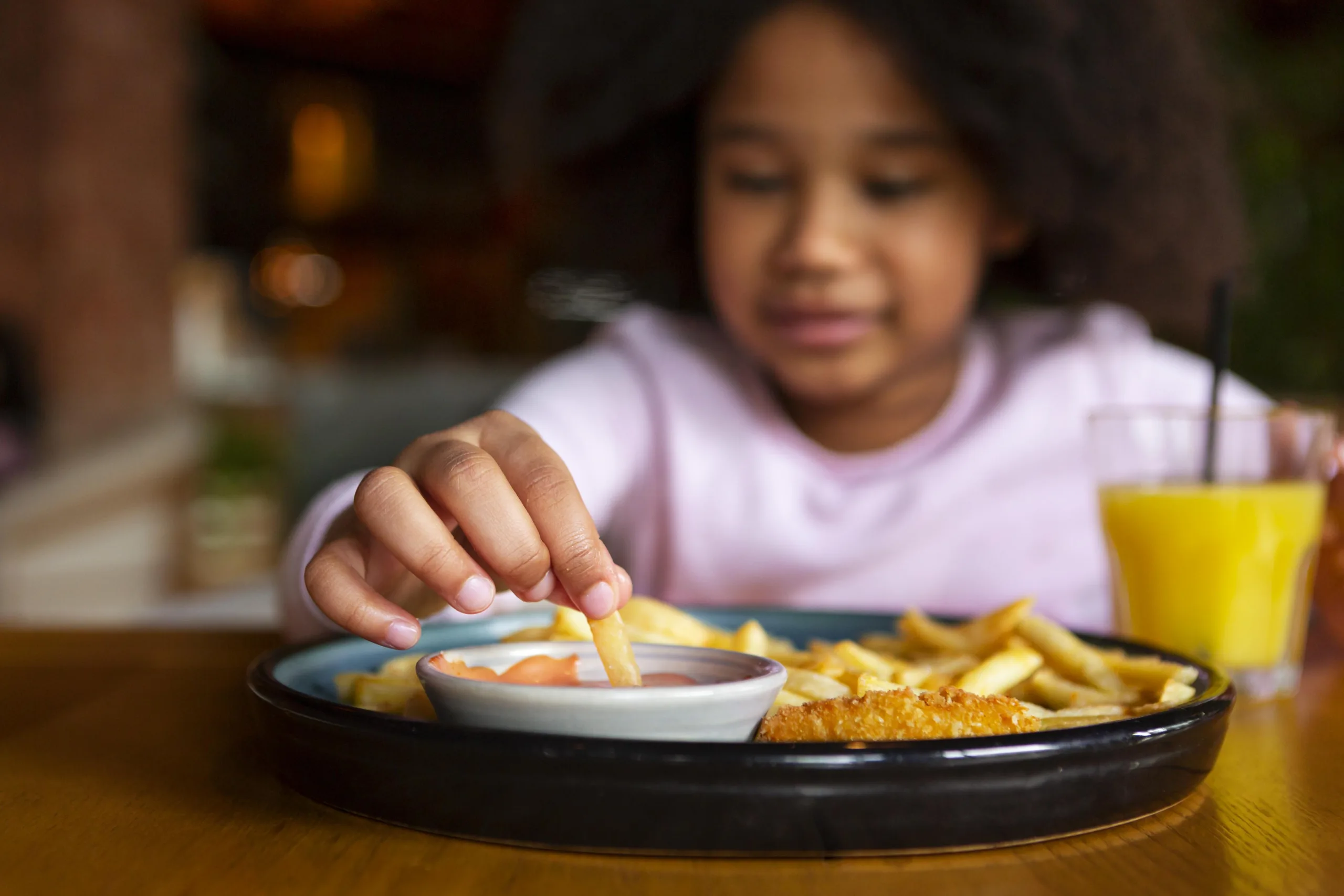 criança come batatas fritas