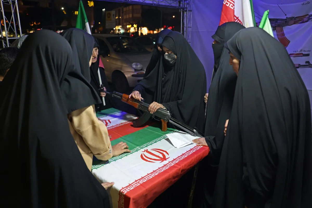 Militar iraniano orienta mulheres sobre uso de arma em praça de Teerã, em 17 de maio de 2026