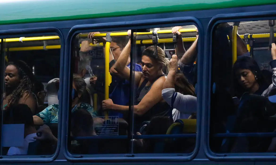 Passageiros aglomerados em ônibus são fotografados da janela