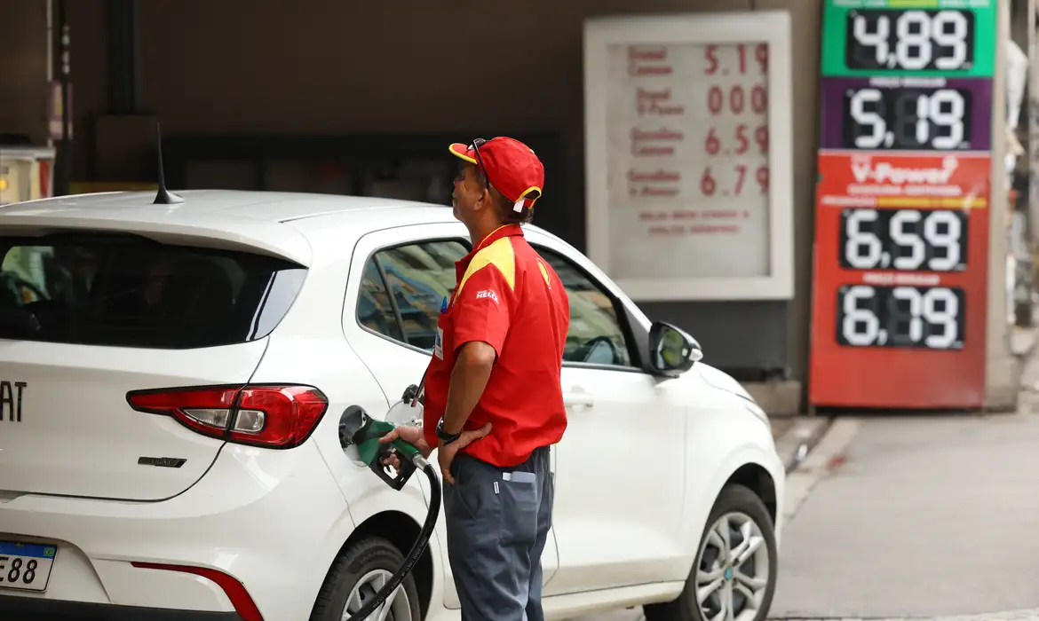 Frentista abastece carro em posto de gasolina