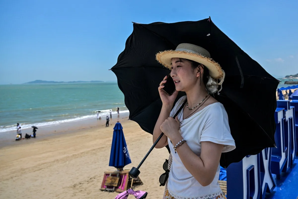 Uma mulher fala ao telefone perto de uma praia em Xiamen, na província de Fujian, no sudeste da China, em frente às Ilhas Kinmen de Taiwan, em 25 de maio de 2026