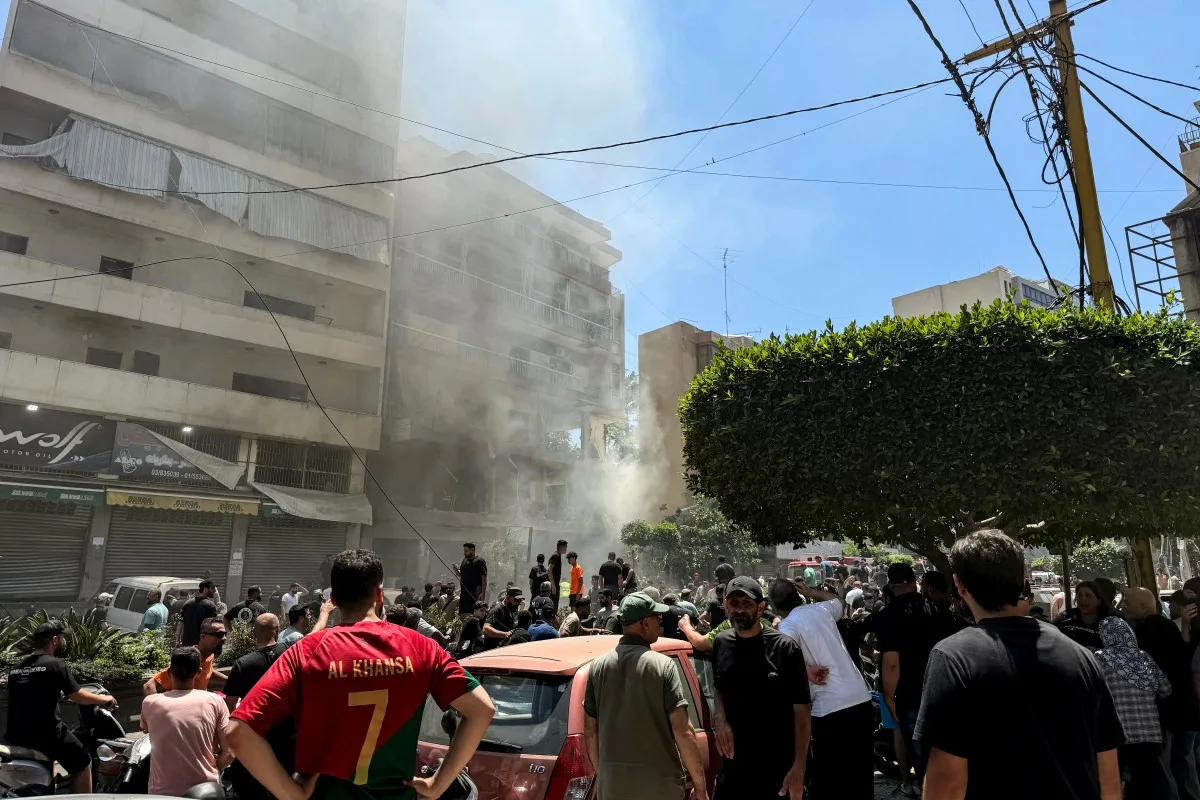 Pessoas se reúnem no local do ataque aéreo israelense que atingiu um prédio nos subúrbios do sul de Beirute em 14 de junho