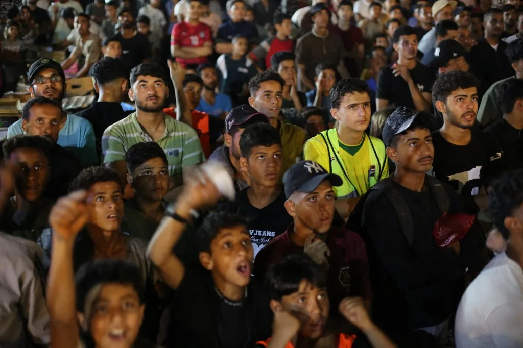 Palestinos assistem à partida do Grupo G da Copa do Mundo da FIFA de 2026 entre Bélgica e Egito em um telão instalado no campo de refugiados de Nuseirat, na Faixa de Gaza, Palestina, em 15 de junho de 2026. A exibição reuniu moradores do campo para acompanhar o torneio sediado pelos Estados Unidos. Hassan Jedi / Anadolu (Foto de Hassan Jedi / ANADOLU / Anadolu via AFP)