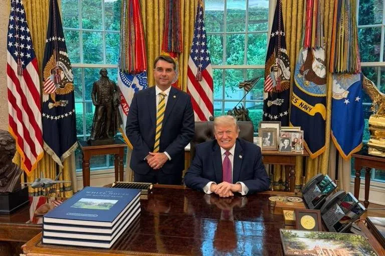 donald trump e flavio bolsonaro sentados na mesa presidencial na casa branca