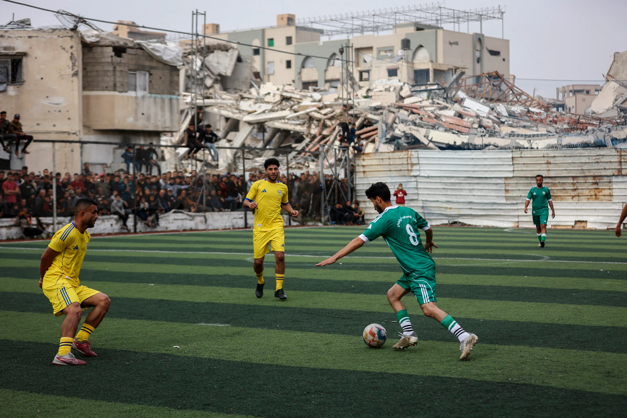 Jovens jogam partida de futebol na Faixa de Gaza em área bombardeada por Israel