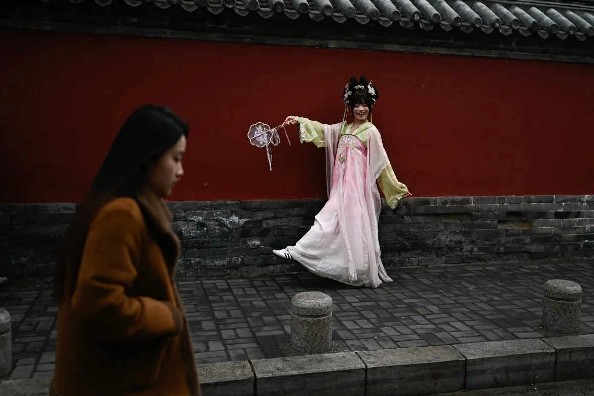 Uma mulher vestindo um traje tradicional chinês posa para uma foto ao lado da Torre do Tambor, em Pequim, em 9 de abril de 2026